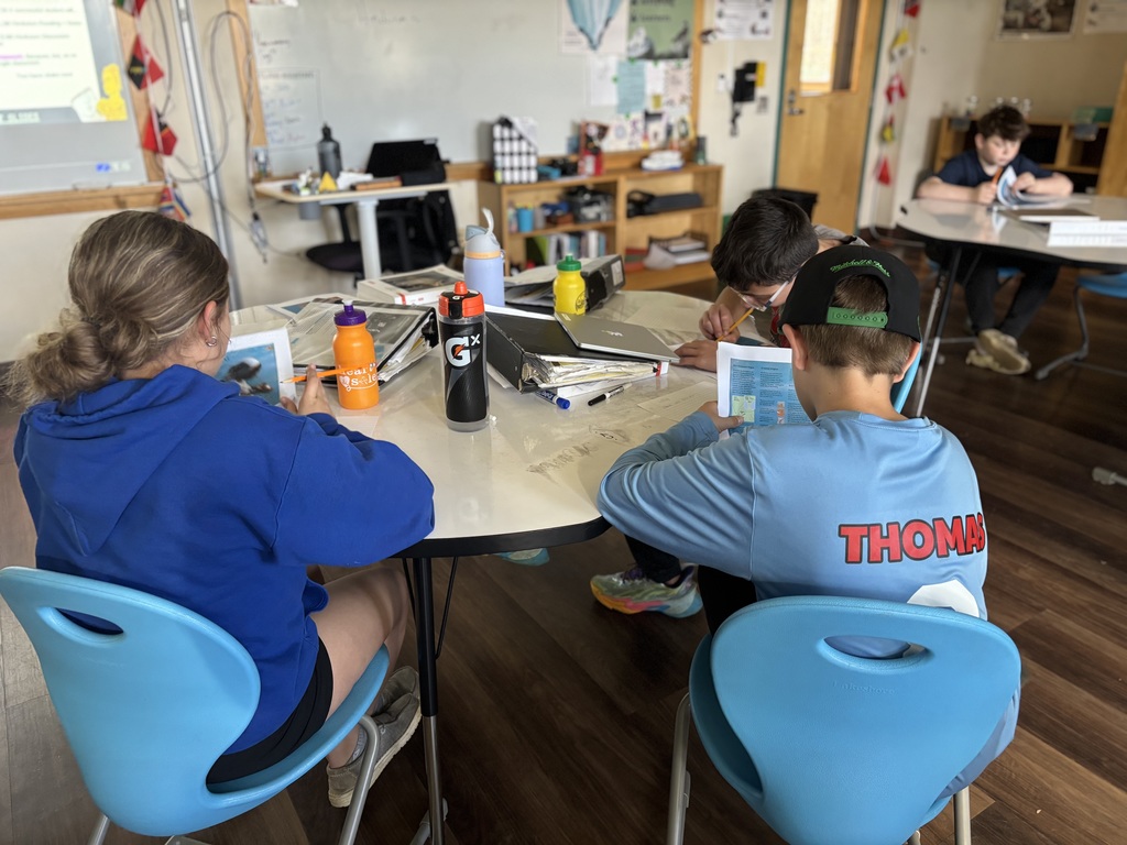 a table of three 7th graders working on their work in social studies