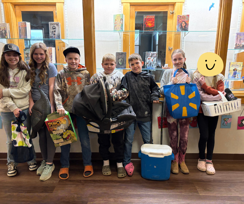 a group of 5th grade students hold various students (cereal box, tote bag, baby carrier, cooler, basket, walmart bag).