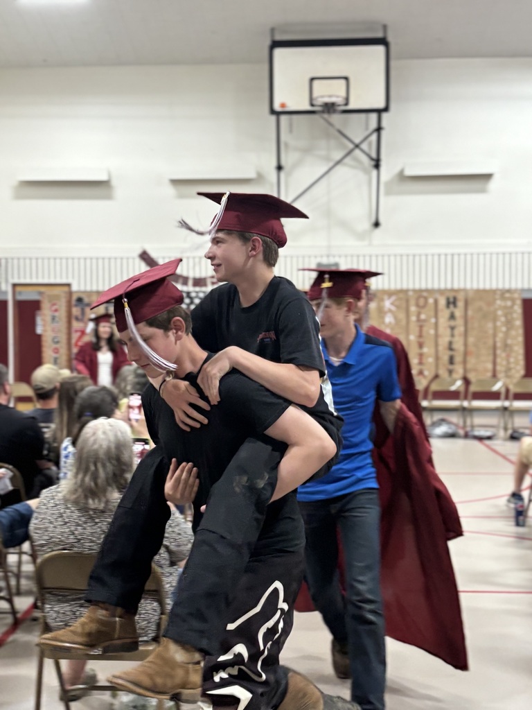 one 8th grade boy givers another a piggy back ride as they do their procession walk out