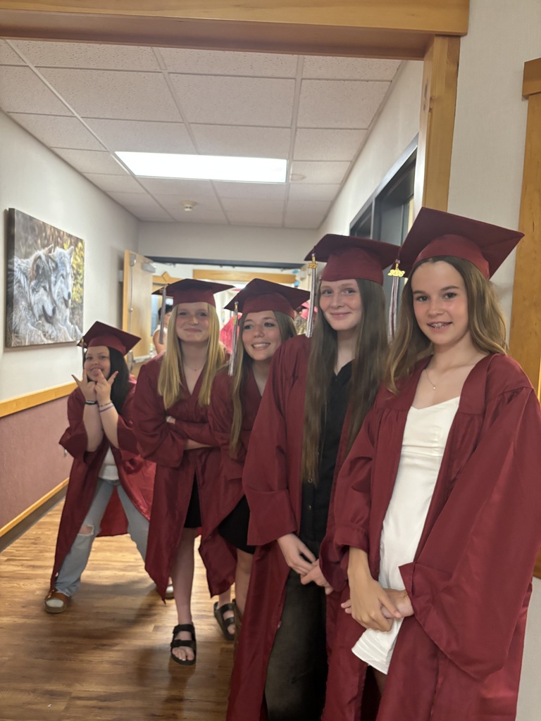 a group of 8th grade girls wearing their caps and gowns and smiling for the camera before they walk