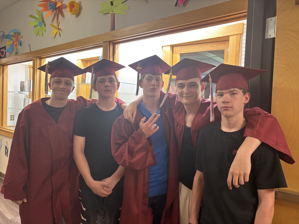 a group of 8th grade boys wearing their caps and gowns and smiling for the camera before they walk
