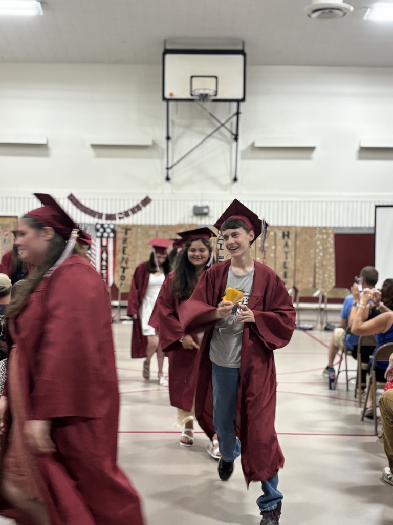 the 8th graders are walking out after graduating. An 8th grade boys holds monopoly money as a joke