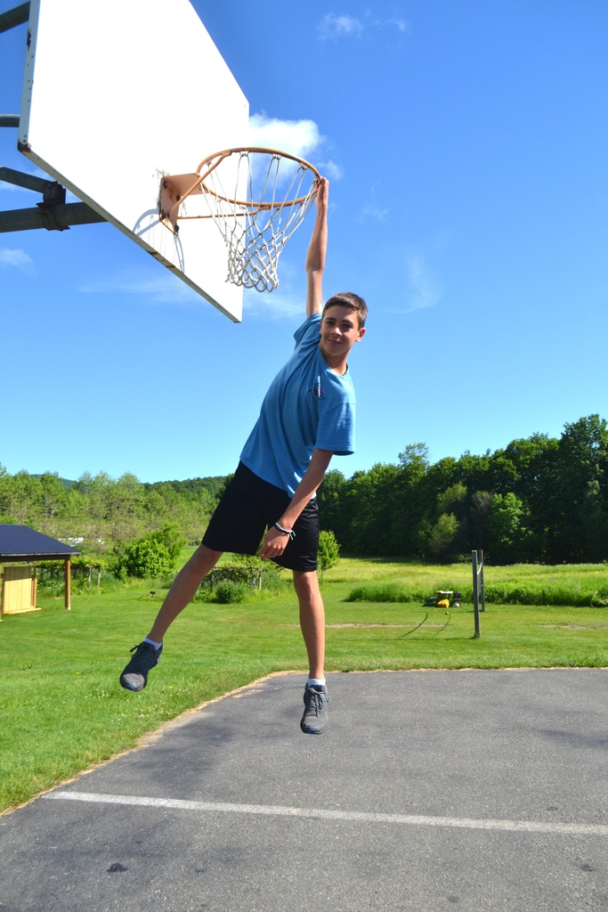 7th grade student hanging from the basketball hoop 