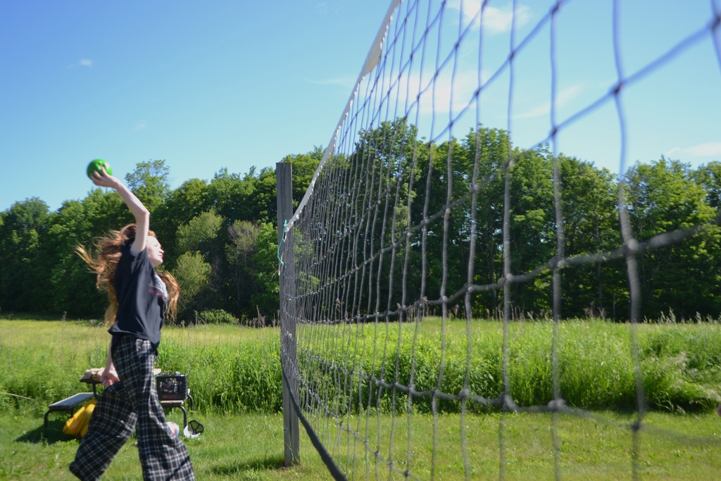 a 6th grader spikes a ball over the volley ball net