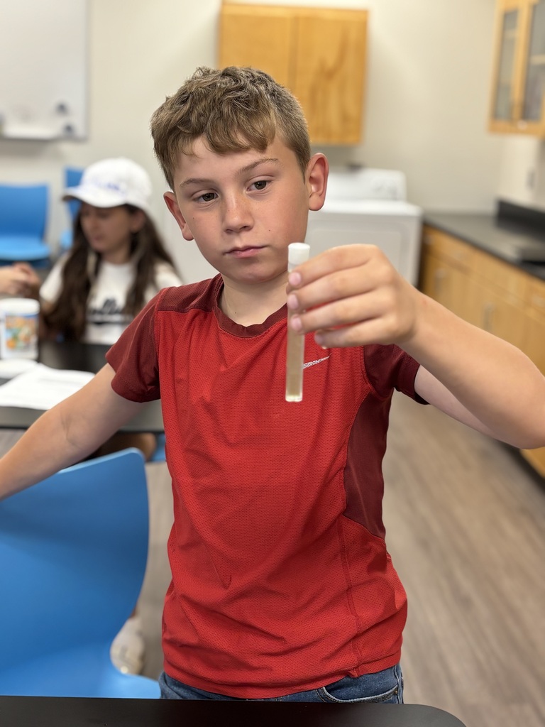 A rising 6th grade boy looks at his water sample in science for step-up day