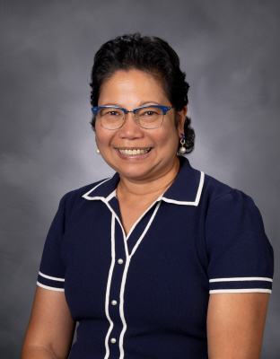 Ms. Phun's school picture. She's wearing a blue collared shirt and blue glasses and is smiley widely
