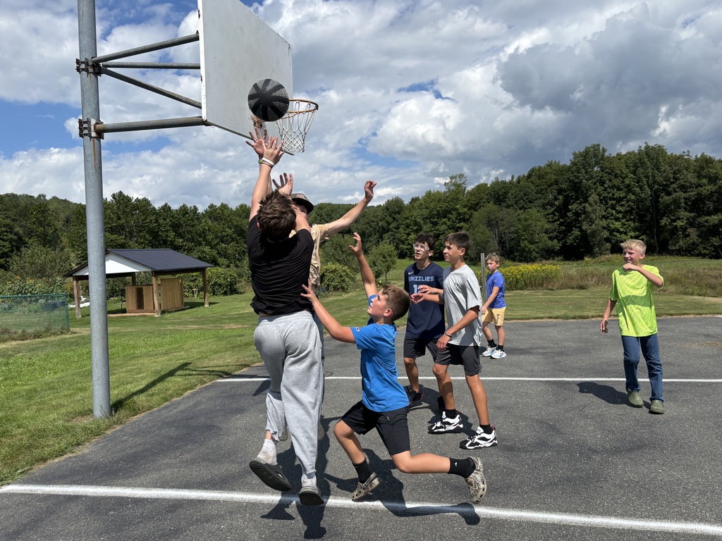 a group of 6th-8th grade boys plays basket ball and tries to get the ball in the hoop