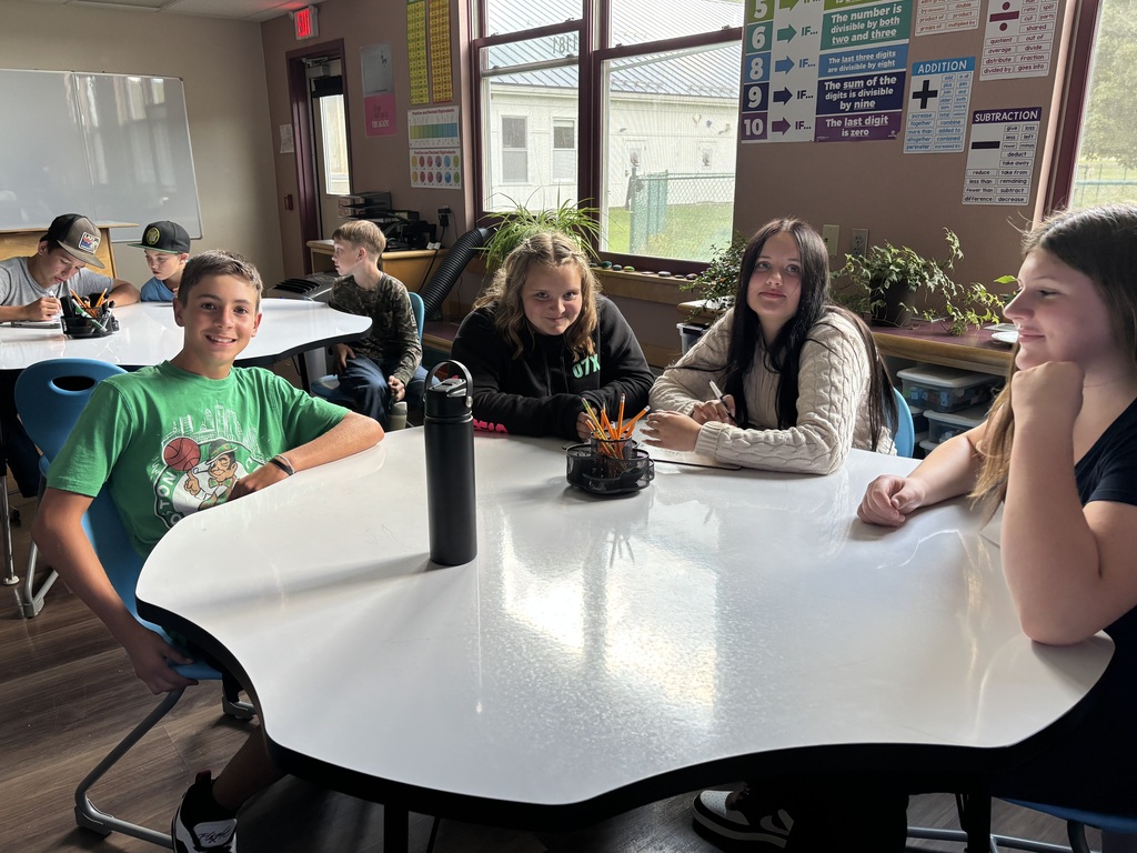 a group of 8th graders smile at the table in math class