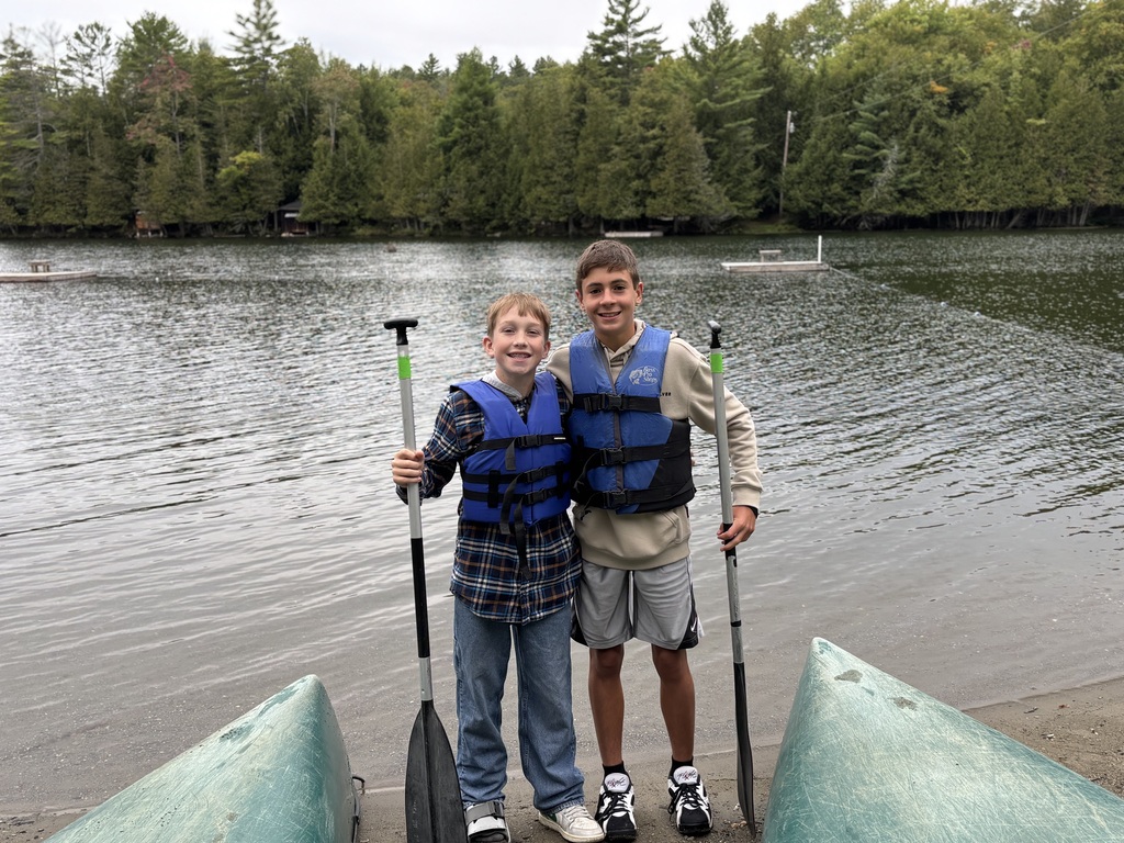 Two 8th grade boys pose with lifejackets on in front of Hosmer Pond