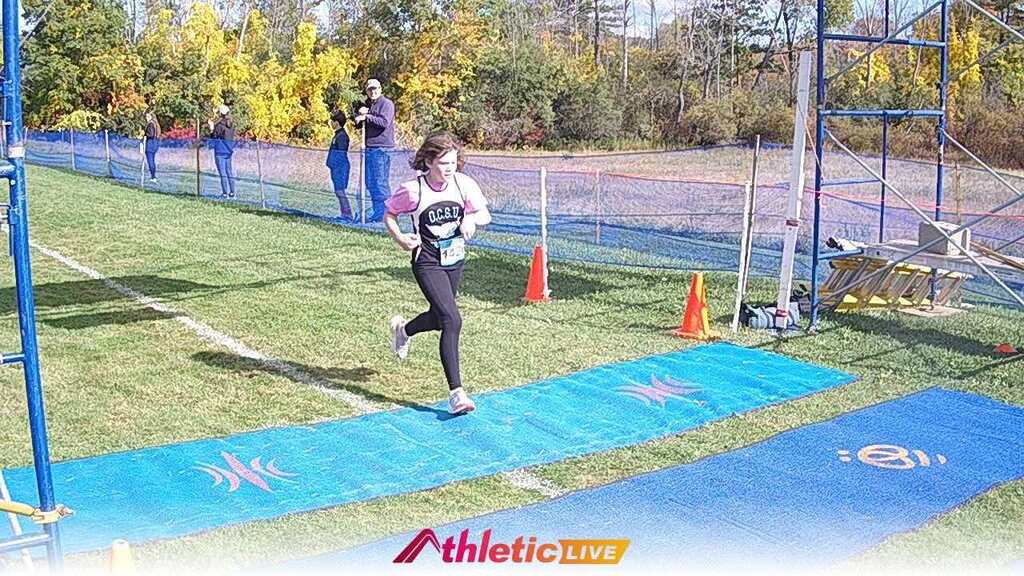 A 6th grade student running across the finish line. 