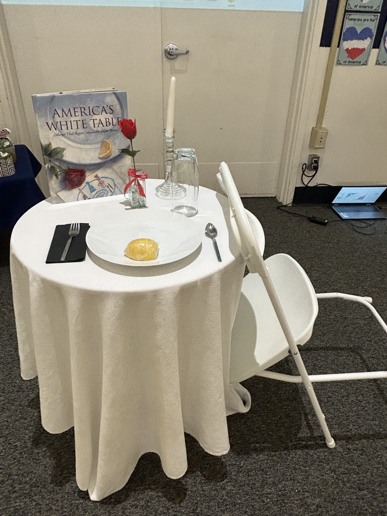 a table with white linen with an empty chair 