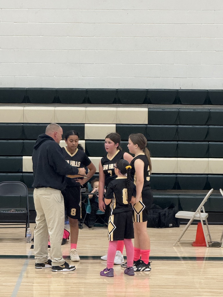 Coach Clint with 4 of his players in a huddle in a gym