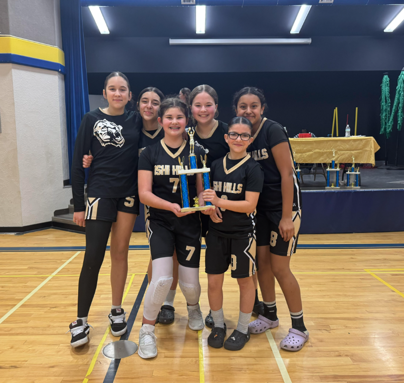 6 Ishi Hills Girls Basketball Players in black uniforms holding a blue trophy.