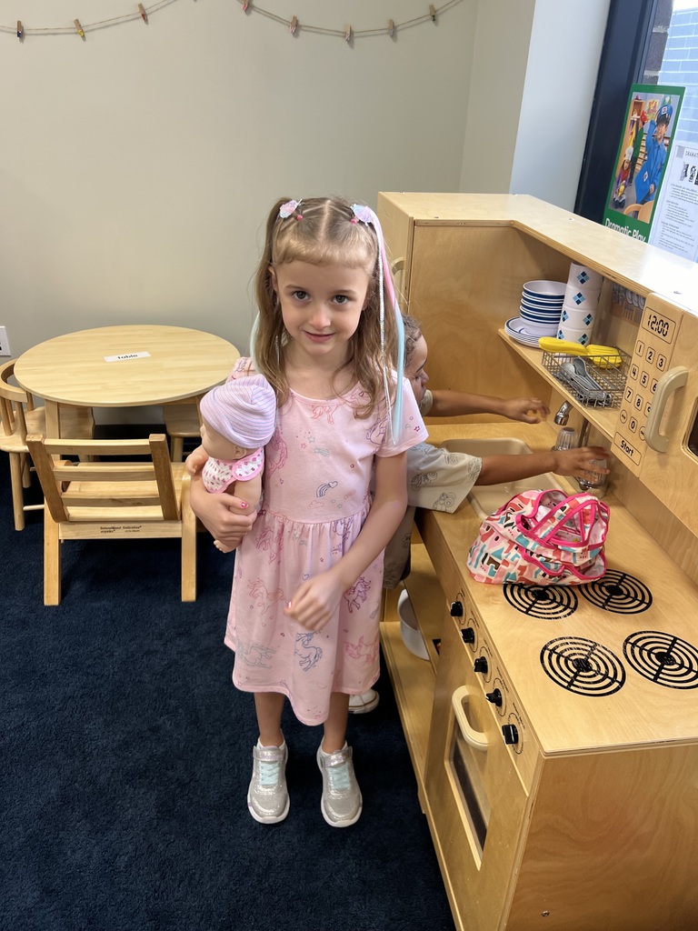Oskaloosa preschooler playing with a baby doll and kitchen set on her first day of school. 
