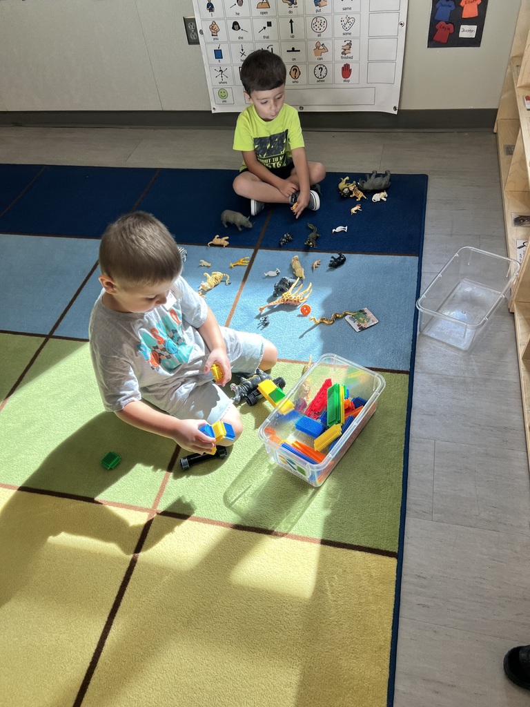 Two preschoolers playing with toys on their first day of school. 