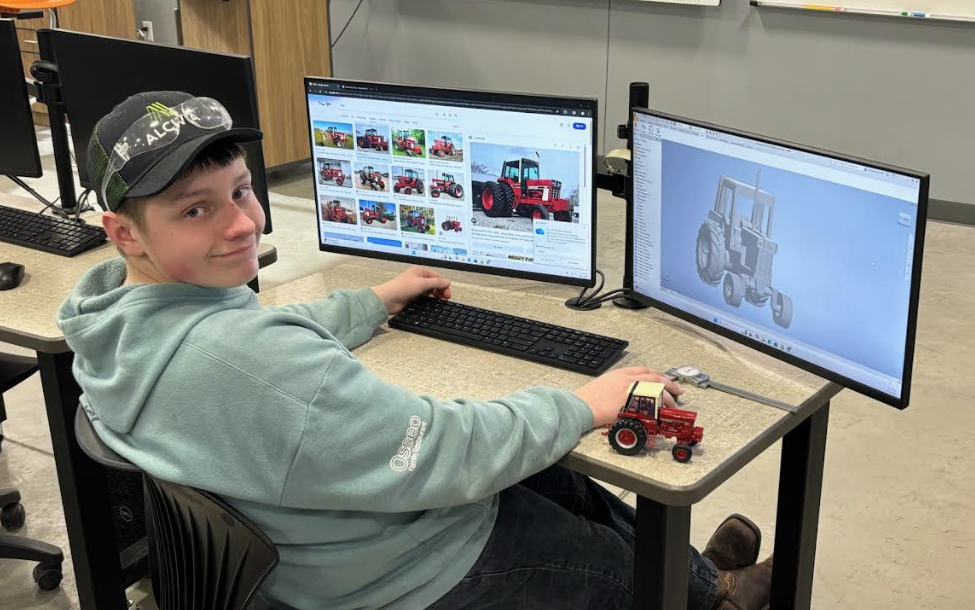 Student working on computers with tractor model 