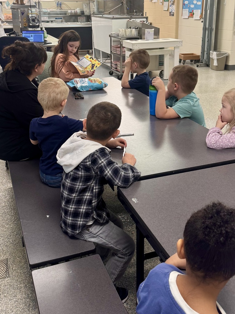 Student reading to younger students