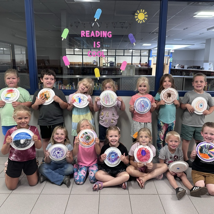 14 students posing with art projects 