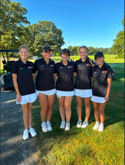 five girls in black shirts and white skirts at golf course