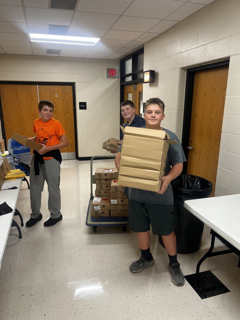 three boys helping deliver boxes in hallways