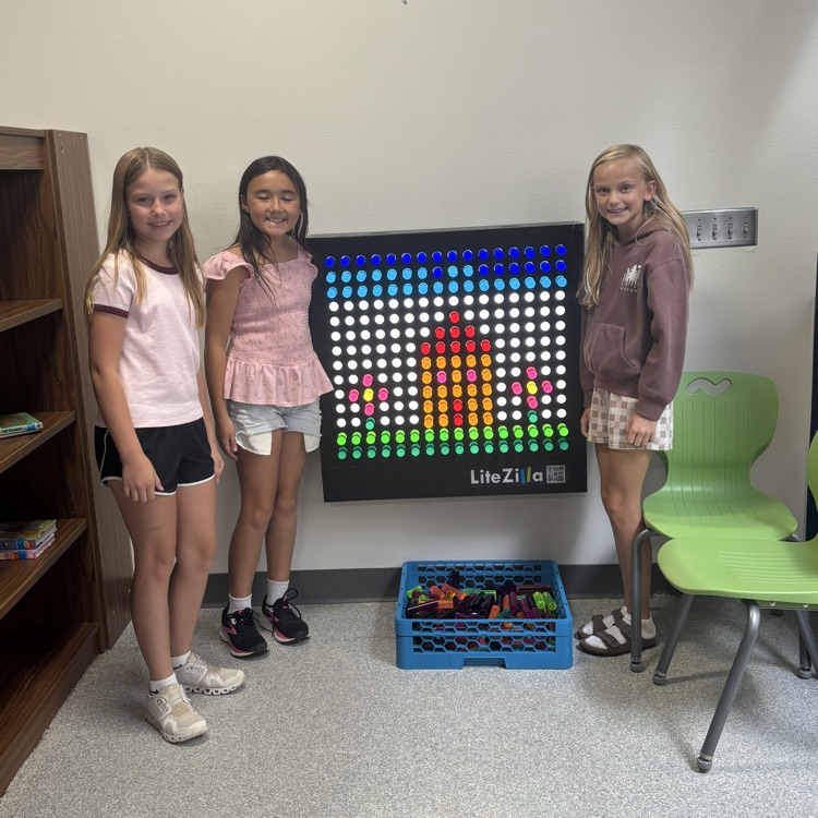 three girls next to the light board with design they created