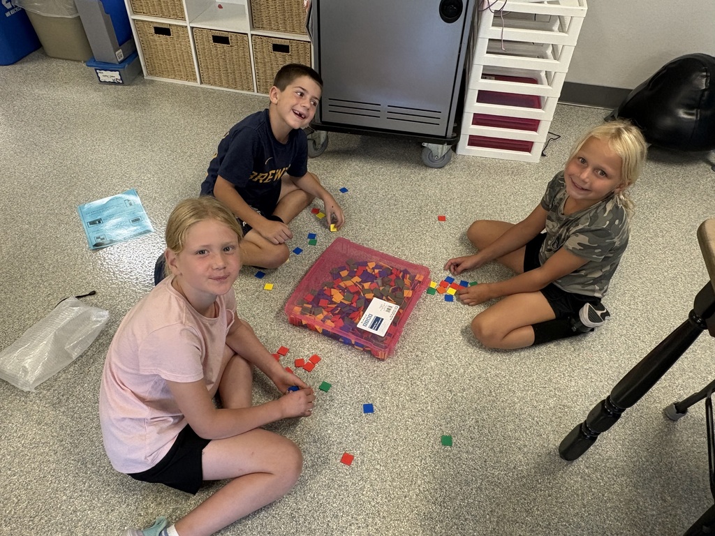 3 students sitting on classroom floor working with square tiles