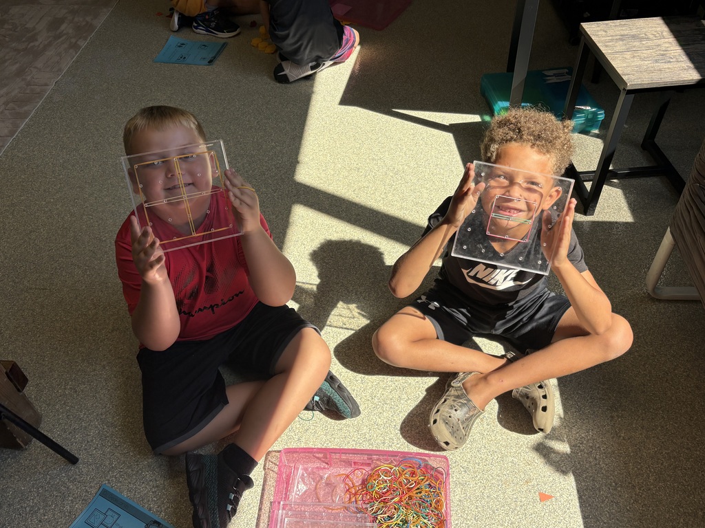 two students looking through geoboards