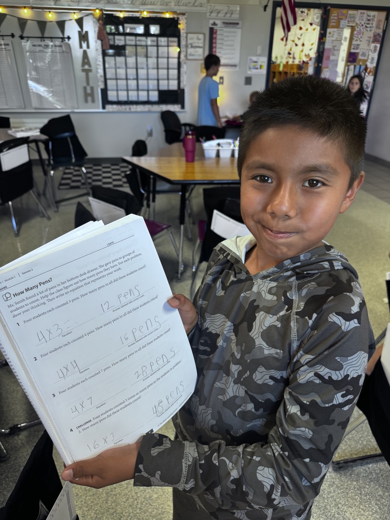 Student holding math workbook with multiplication problems