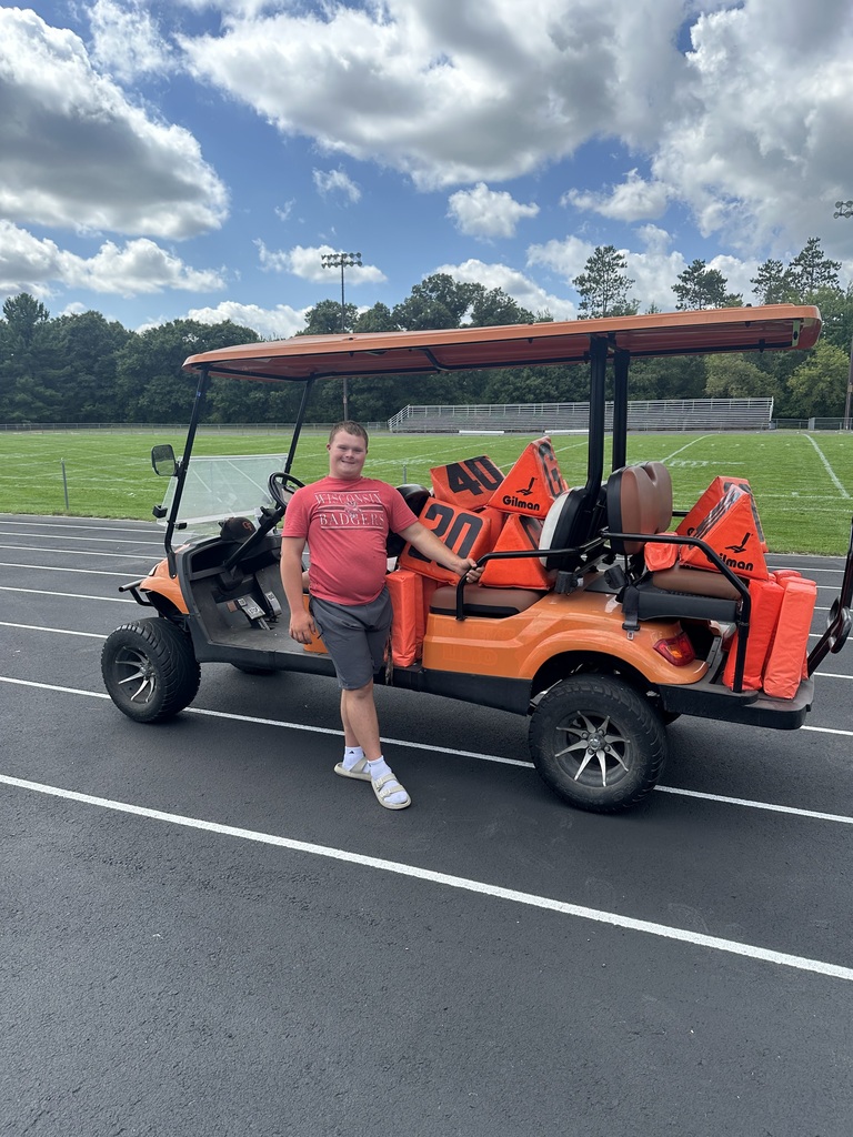 Max posing in front of orange golf cart at football field