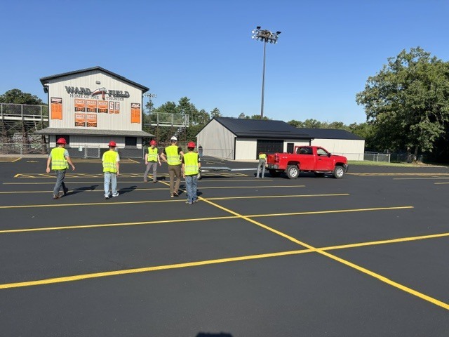 Men in yellow shirts and hardhats in football parking lot