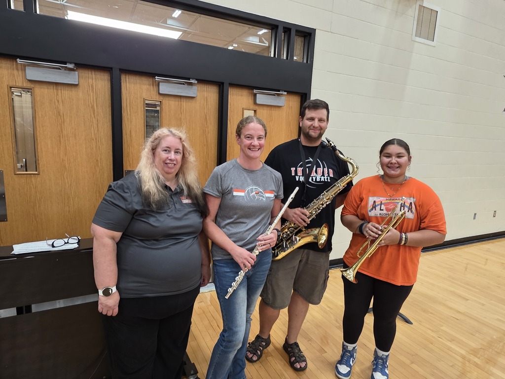 four adults holding band instruments