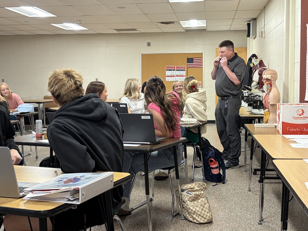 Mr. Korger playing harmonica in front of a class of students