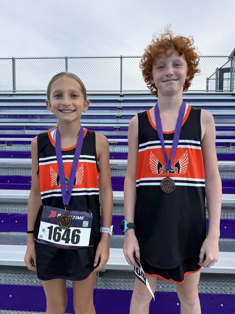 cross country runners MS with medals standing in front of bleachers