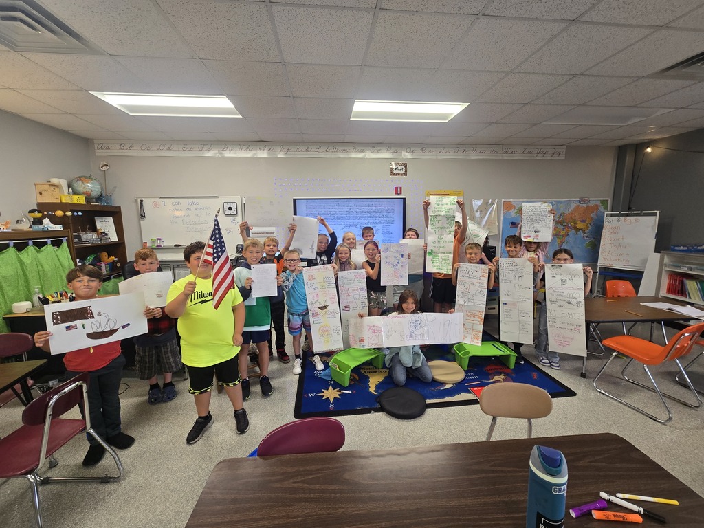 Students in classroom holding up papers