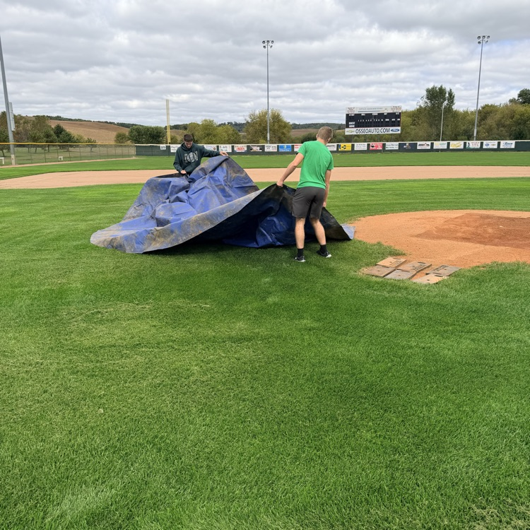 students coving pitching mound on baseball field