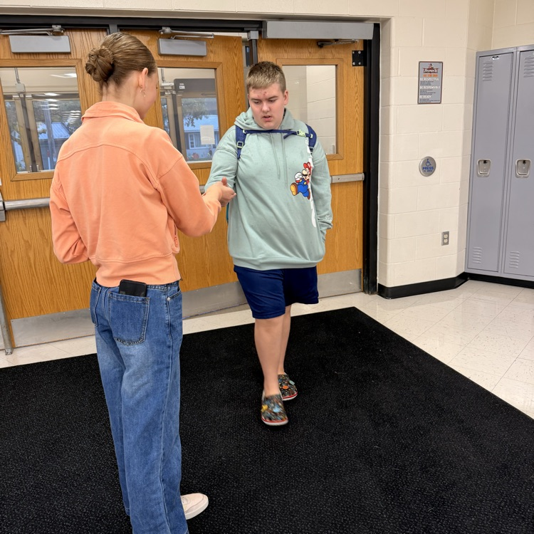 students being greeted as they enter school 