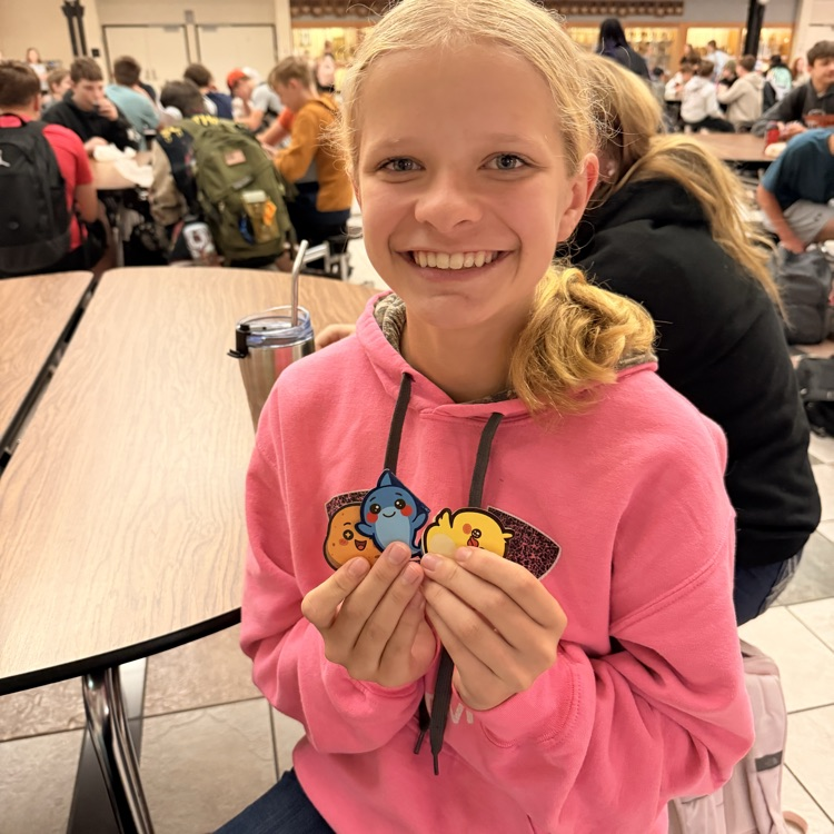 girl in pink sweatshirt holding up stickers 