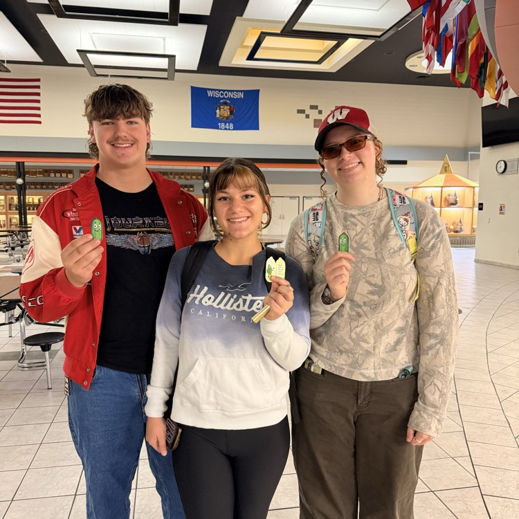 three students holding stickers 