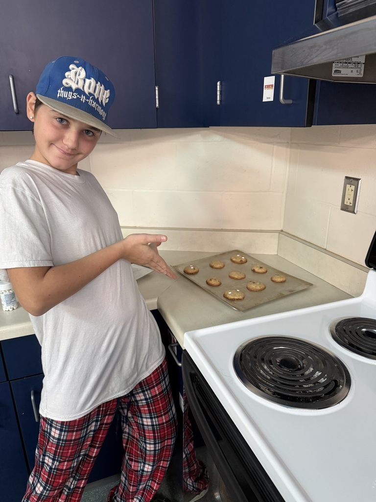student showing baked cookies on cookie sheet