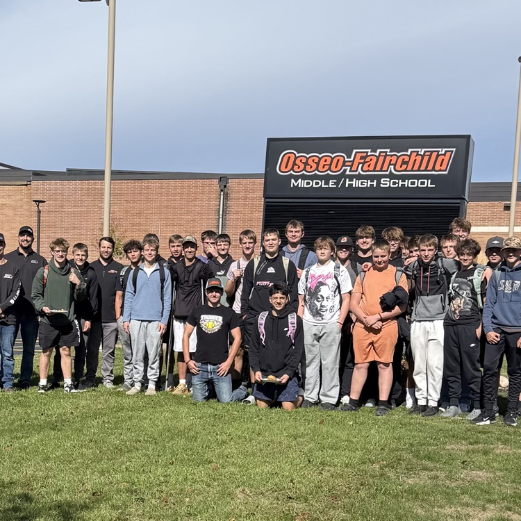 football team posing I. front of Osseo Fairchild sign 