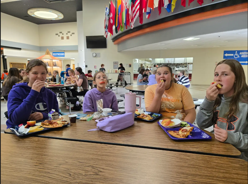students eating apples at lunch tables