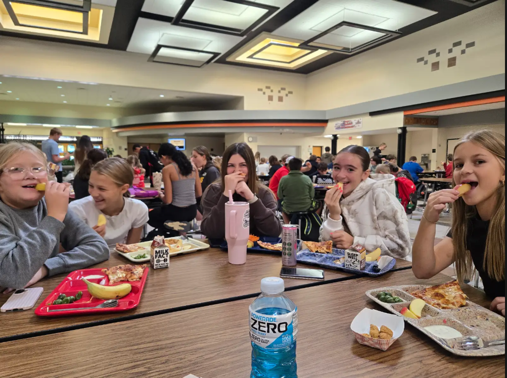 students eating apples at lunch tables