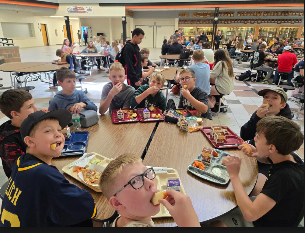 students eating apples at lunch tables