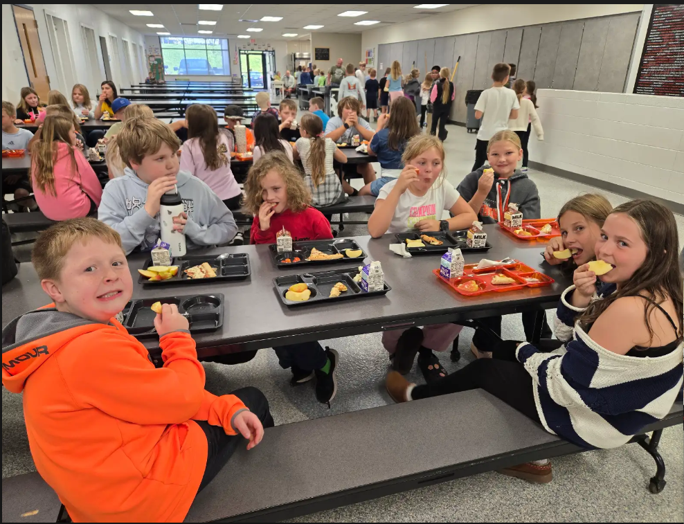 students eating apples at lunch tables