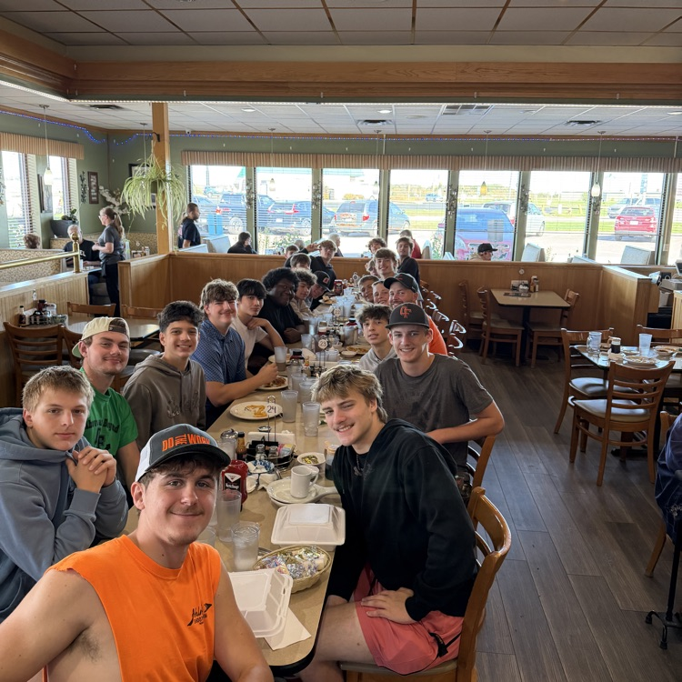 football players sitting at a long table at osseo family restaurant 