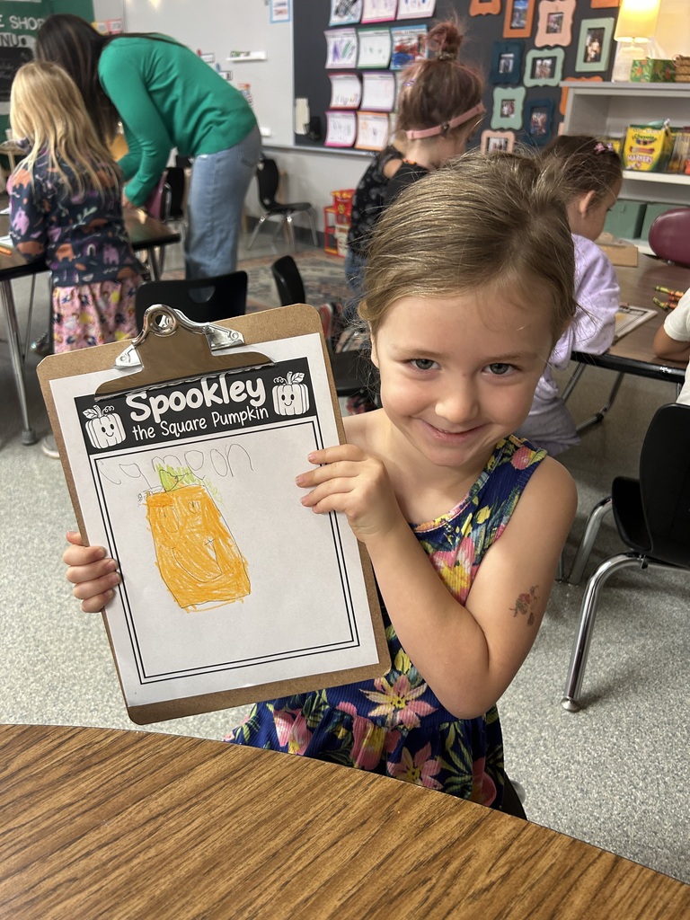 Image Description for accessibility: Student holding artwork