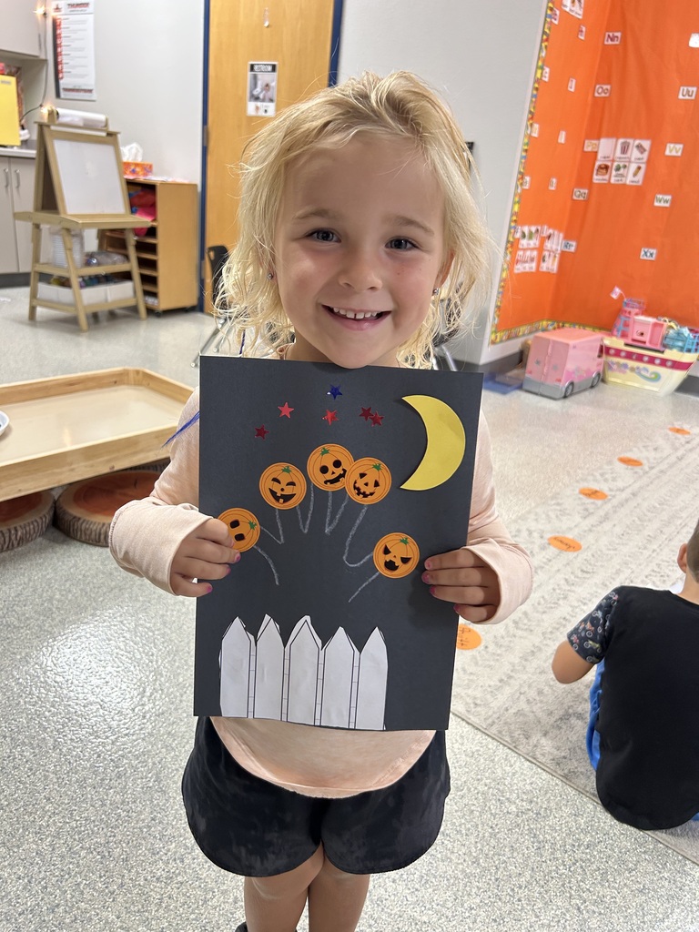 Image Description for accessibility: Student holding 5 little pumpkin project