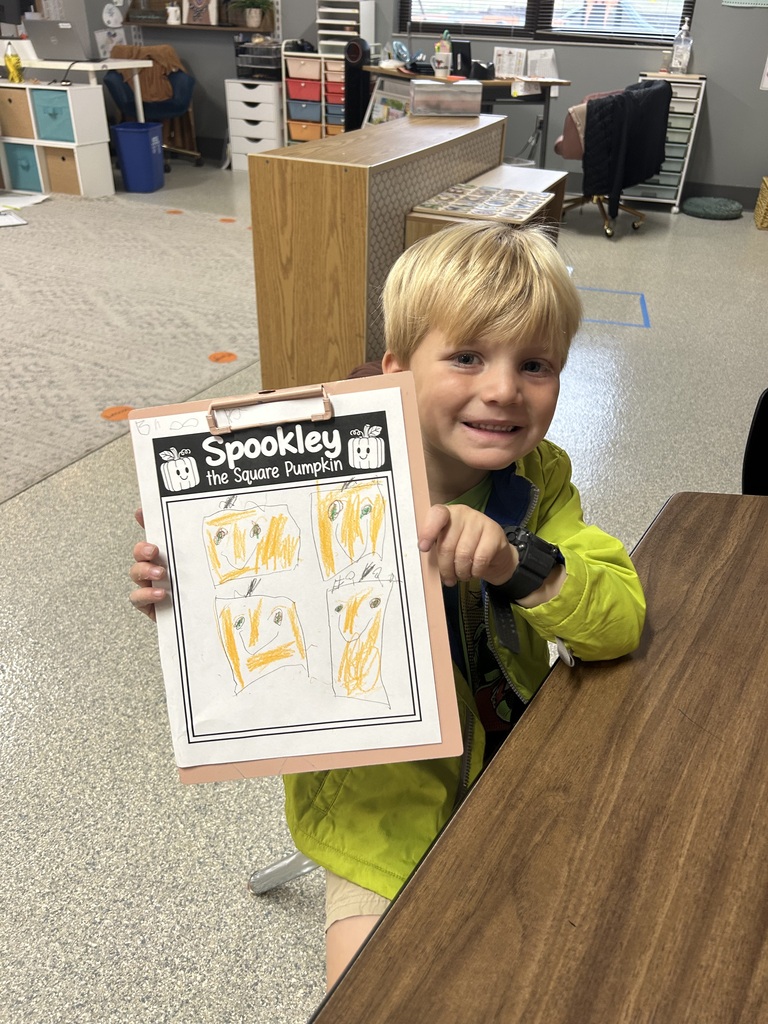Image Description for accessibility: Student holding up clipboard with pumpkin drawing