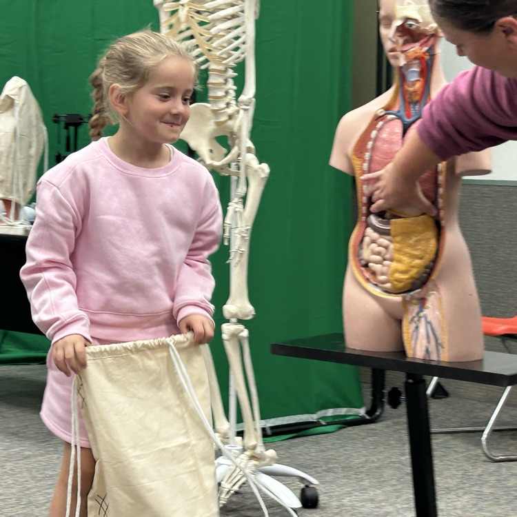 Image Description for accessibility: student holding bag in front of human body model