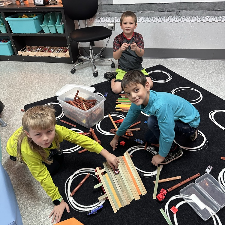 Image description for accessibility:  students on carpet, playing with wooden blocks